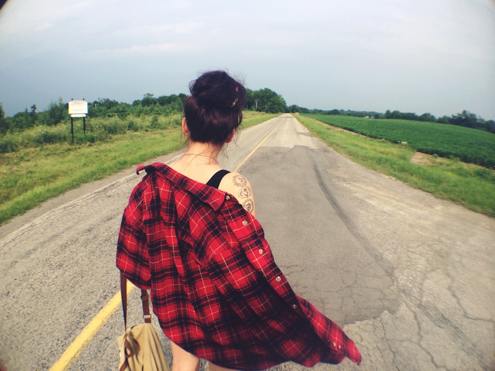 a woman walking down a road with a handbag