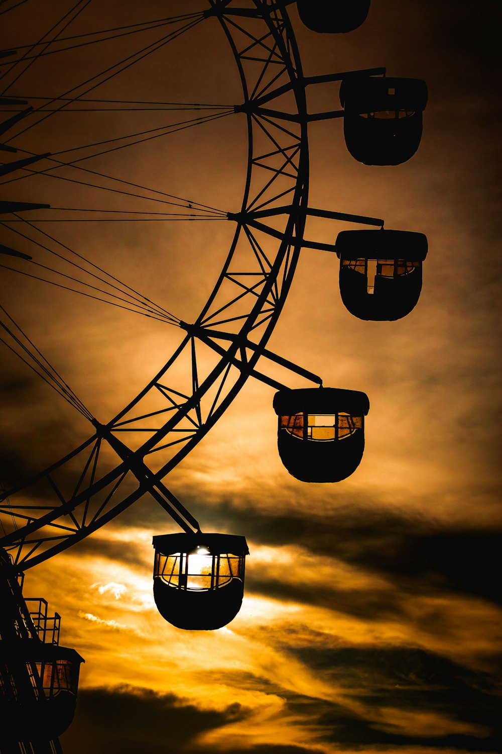 a ferris wheel is silhouetted against a cloudy sky