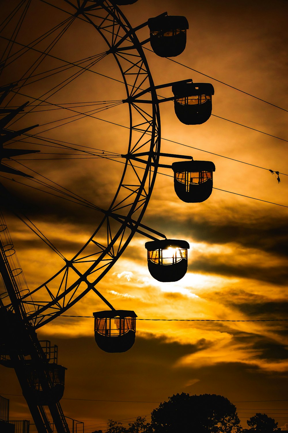 a ferris wheel is silhouetted against a cloudy sky