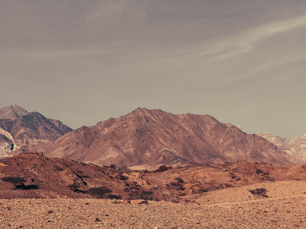 a mountain range in the desert under a cloudy sky