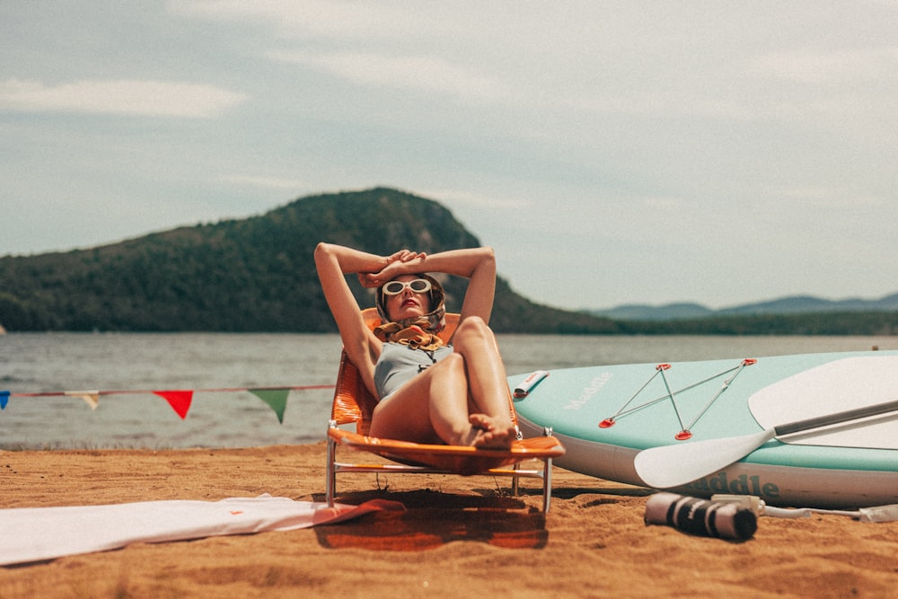 a woman sitting in a beach chair next to a surfboard