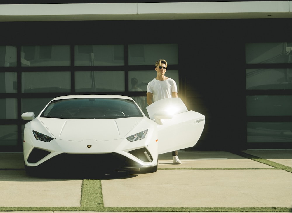a man standing next to a white sports car