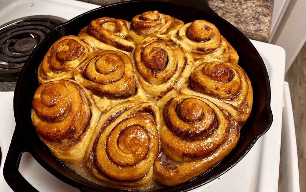 a pan filled with cinnamon rolls sitting on top of a stove