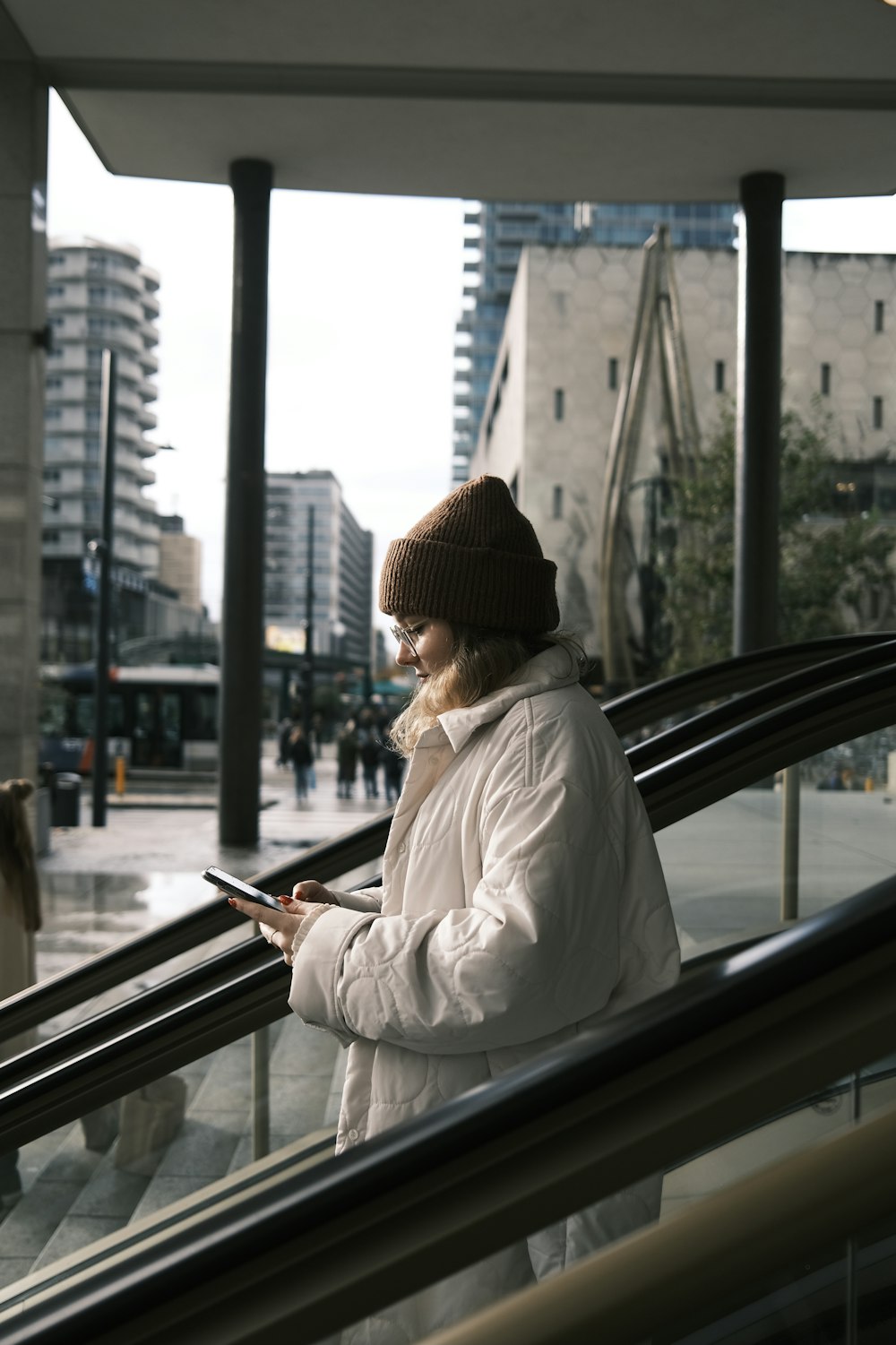 a woman standing on an escalator using a cell phone