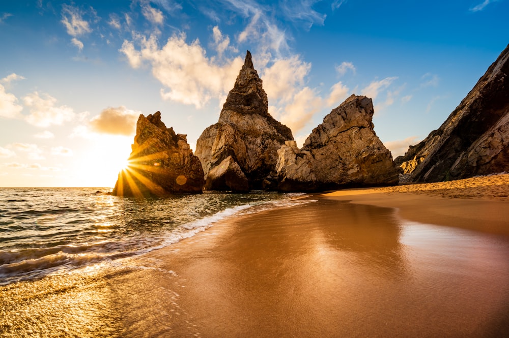 Il sole sta tramontando sulla spiaggia vicino alle rocce