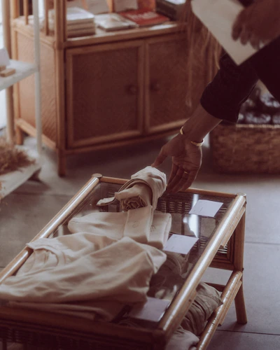 Hands gently feeling soft, colorful cloths spread out on a wooden table.