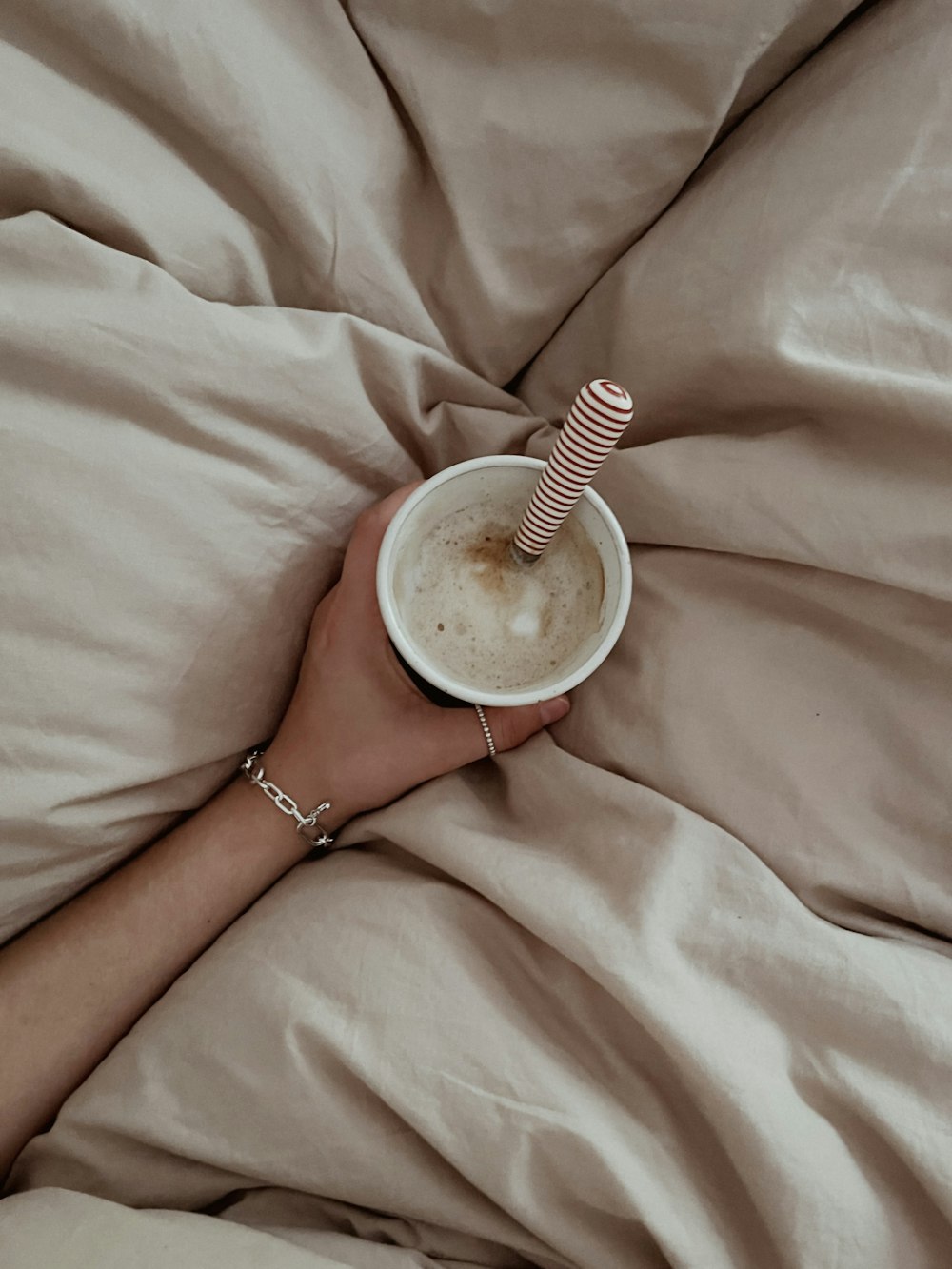 a person laying in bed with a cup of coffee