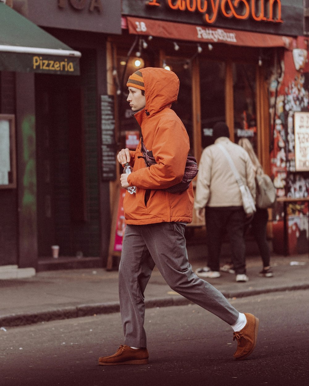 a man in an orange jacket is walking down the street