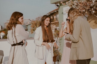 Elegant group of women enjoying a sunset toast on a European terrace overlooking historic city rooftops.