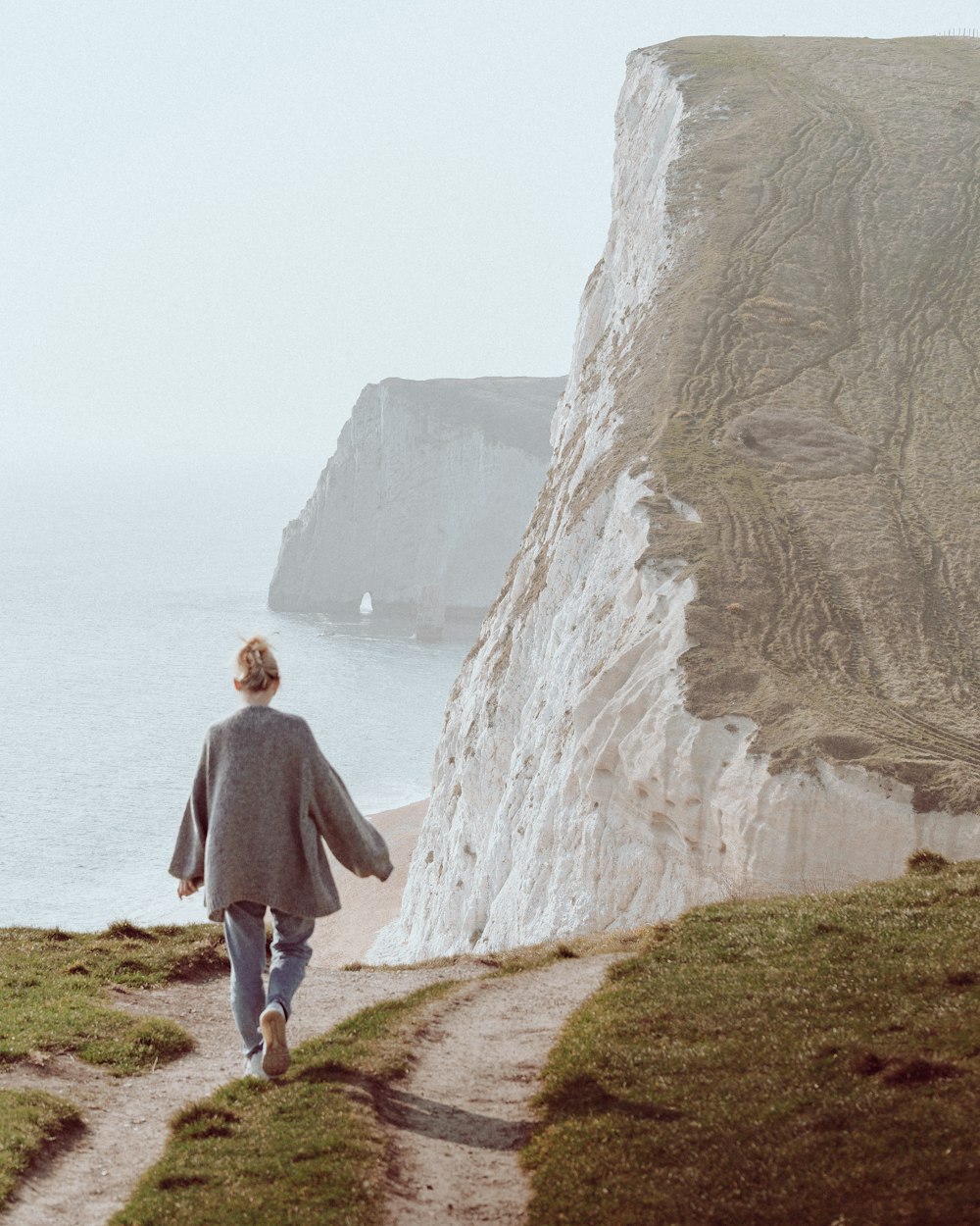 a person walking down a path next to the ocean