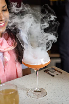 a woman sitting at a table with a drink in front of her