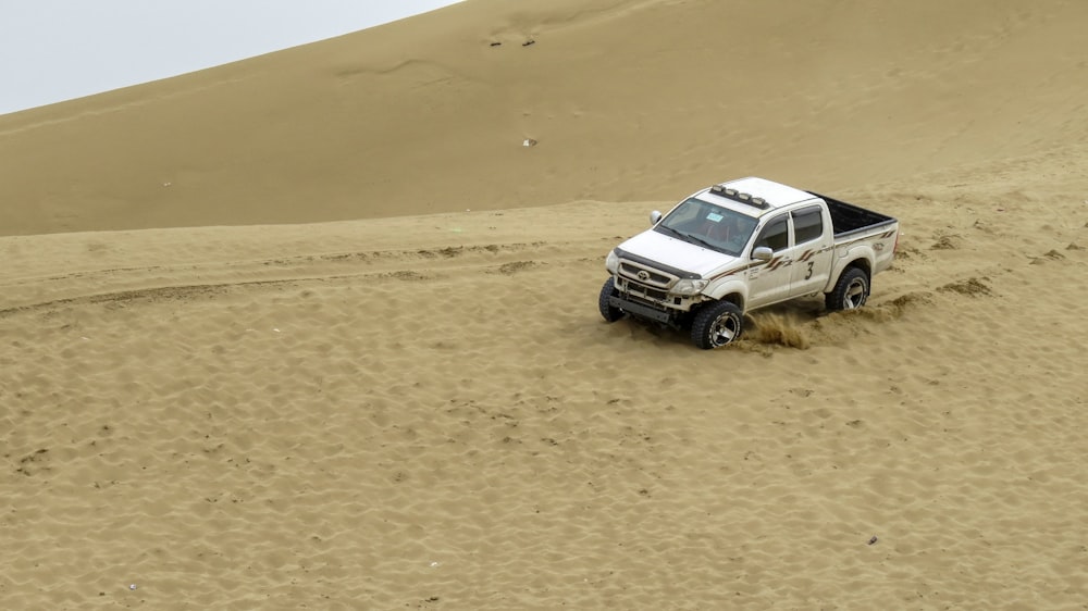 a white truck driving through a sandy area