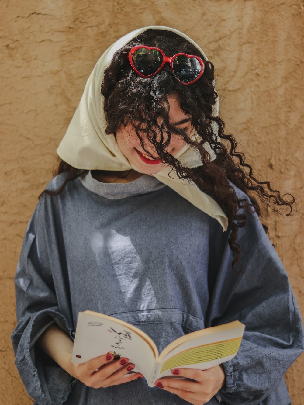 a woman wearing sunglasses and a headscarf is reading a book