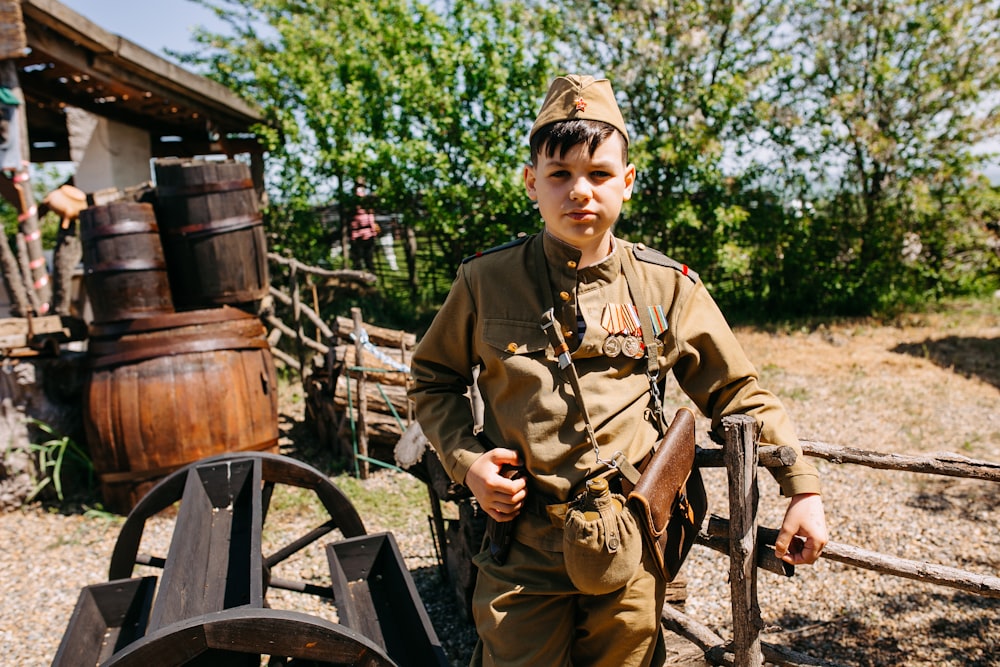 a young boy in a uniform standing next to a wagon