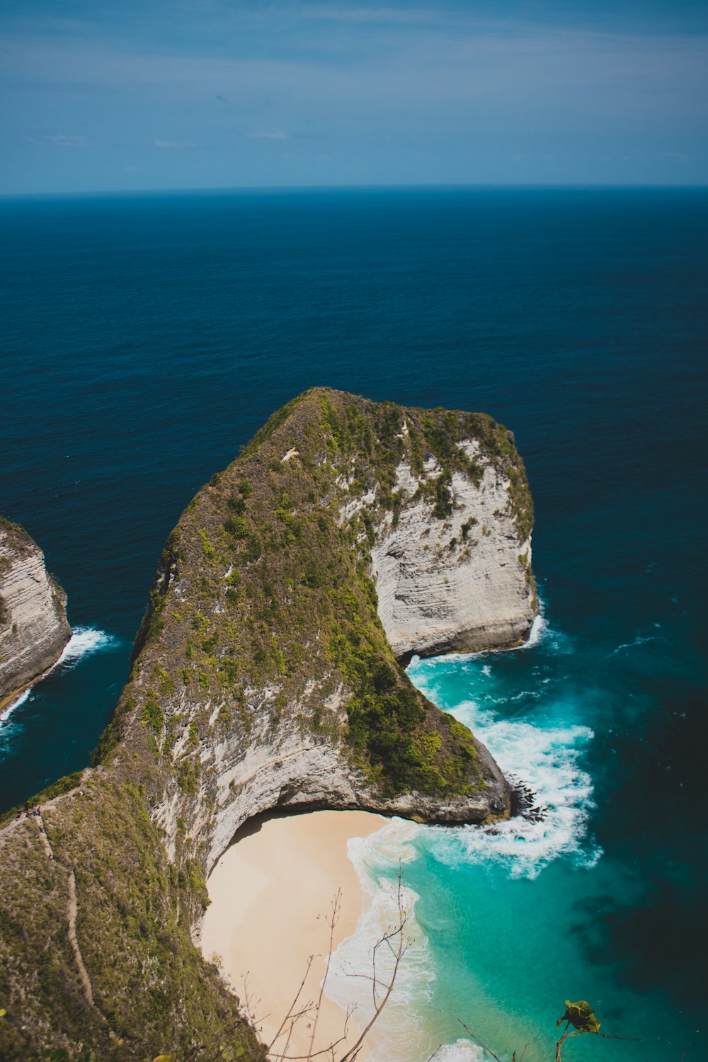 an aerial view of a beach with a rock outcropping