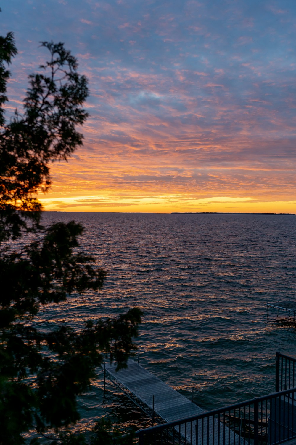 a sunset over a body of water with trees in the foreground