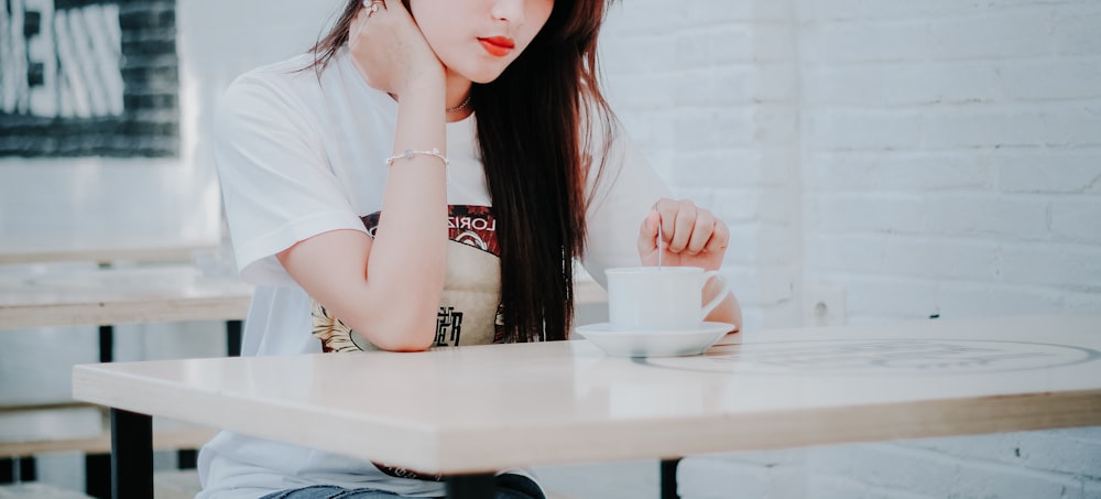 a woman sitting at a table with a cup of coffee