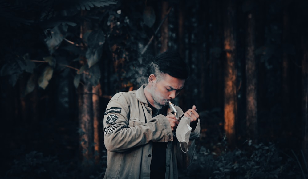 a man standing in a forest smoking a cigarette