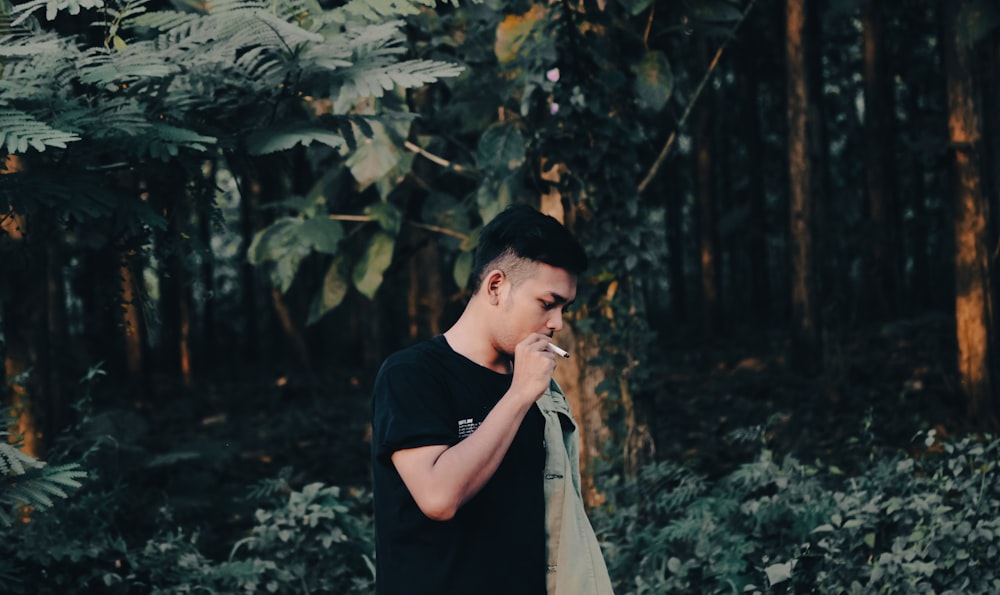 a man standing in a forest smoking a cigarette