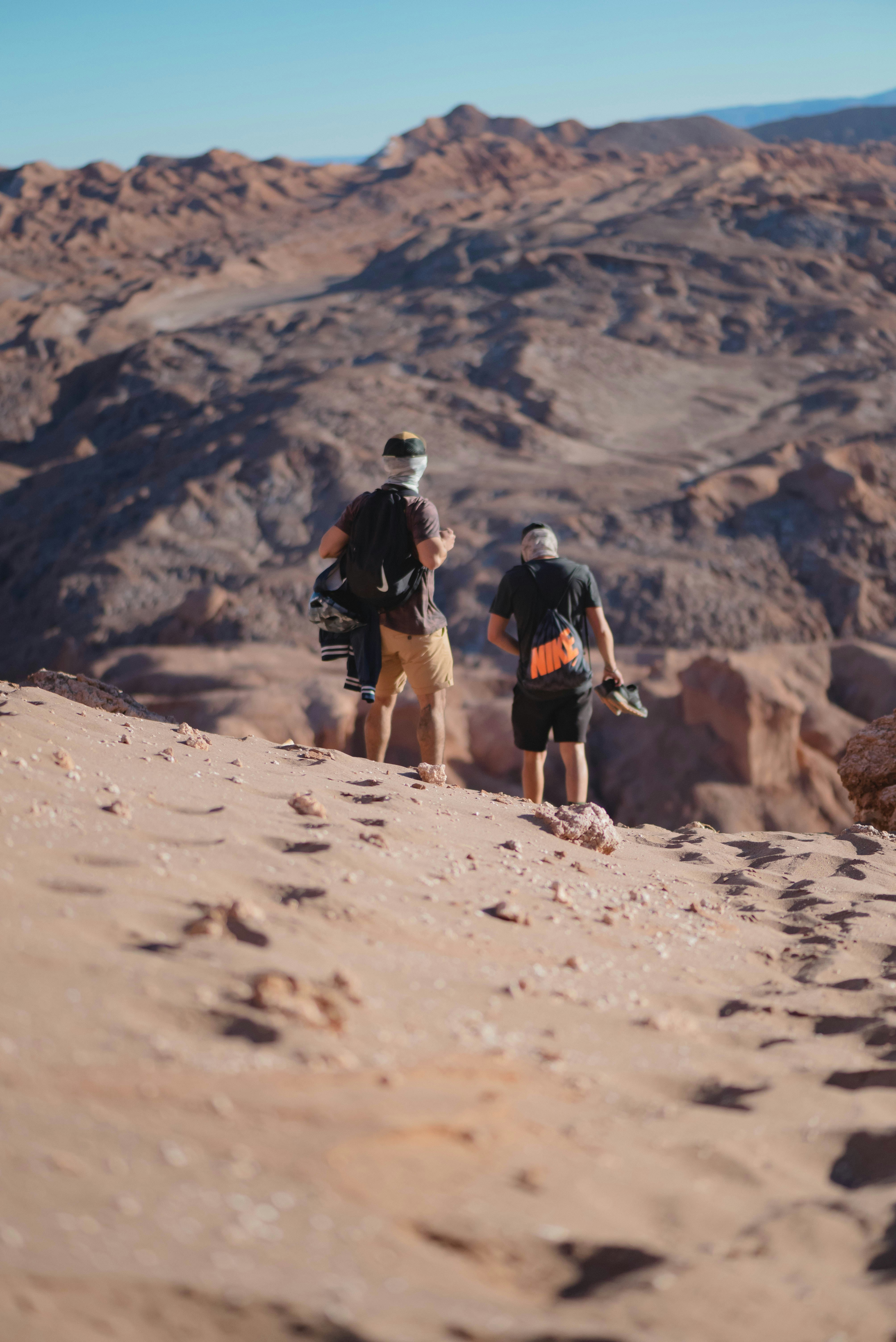 a couple of men walking across a dirt field