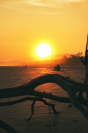 the sun is setting over the water on the beach