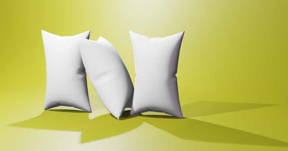 two white pillows sitting next to each other on a yellow background