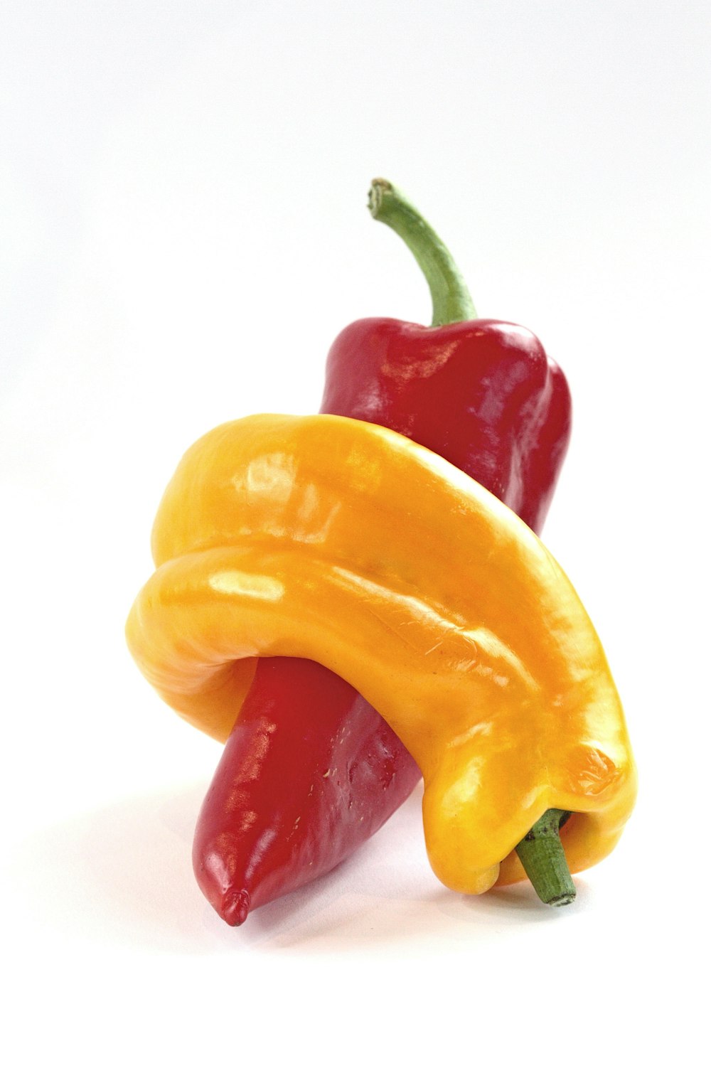 two yellow and red peppers on a white background