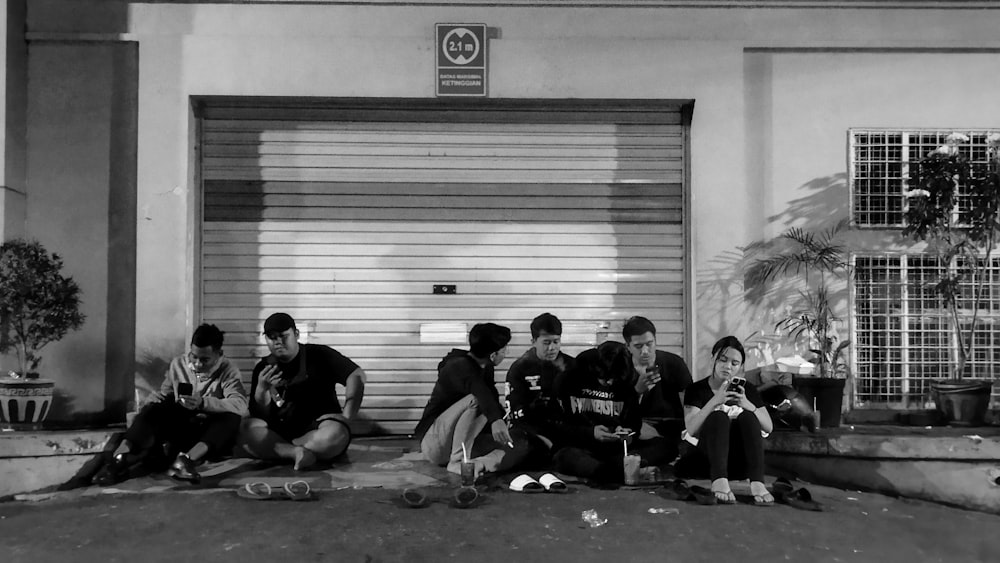 a group of people sitting on the ground in front of a garage