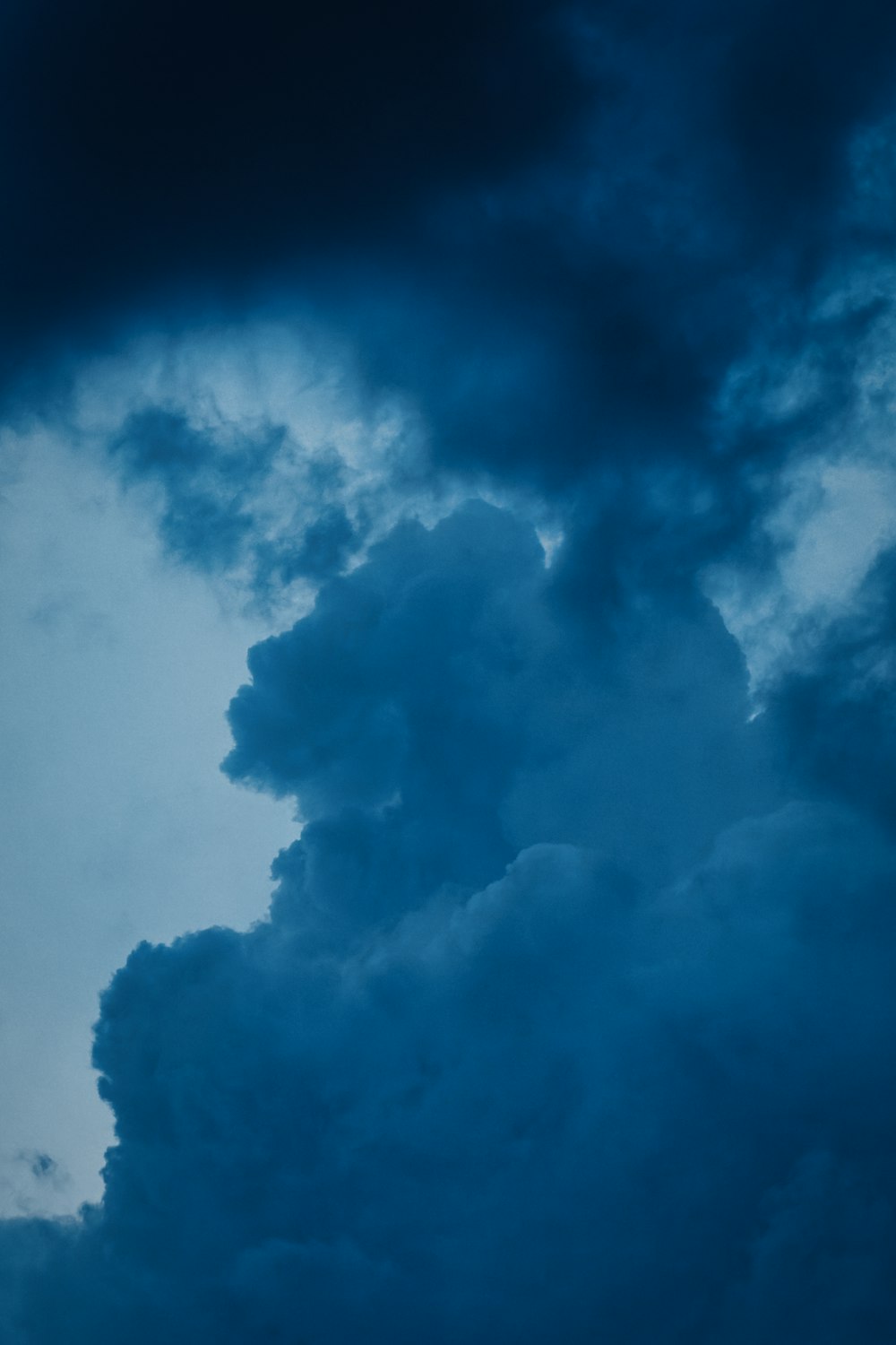 a plane flying through a cloudy blue sky