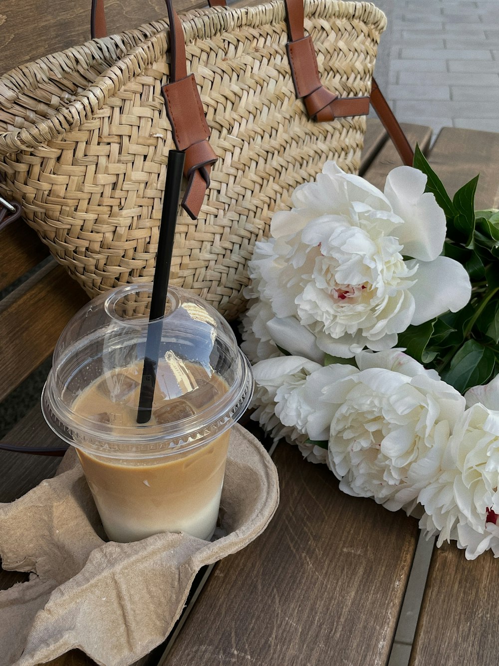 a glass with a drink in it next to a basket of flowers