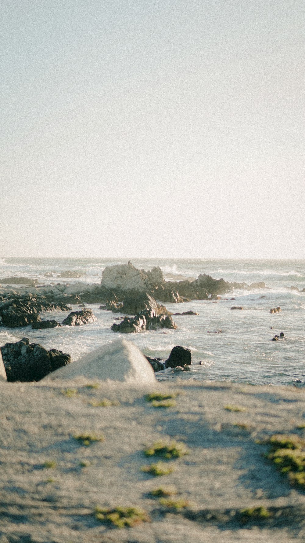 a rocky beach with a body of water in the background