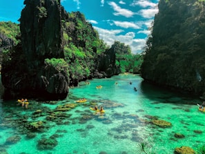 a group of people in a body of water surrounded by large rocks