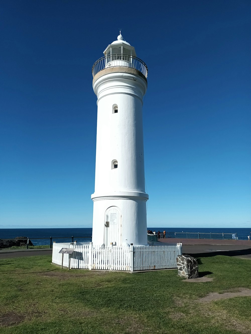 a white lighthouse on a grassy hill