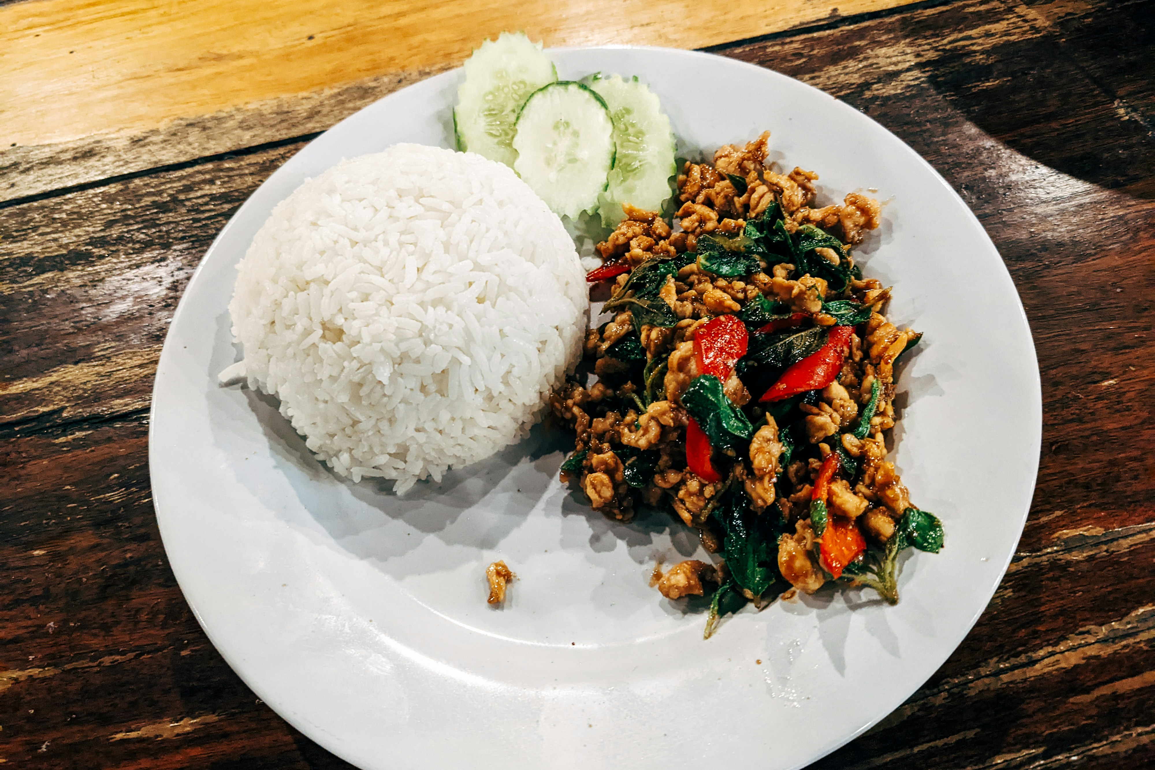 Thai basil chicken stir fry with fried egg over white jasmine rice in a bowl