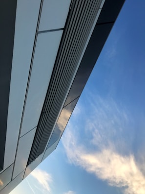 Modern building facade featuring sleek aluminium and glass panels under a clear blue sky.