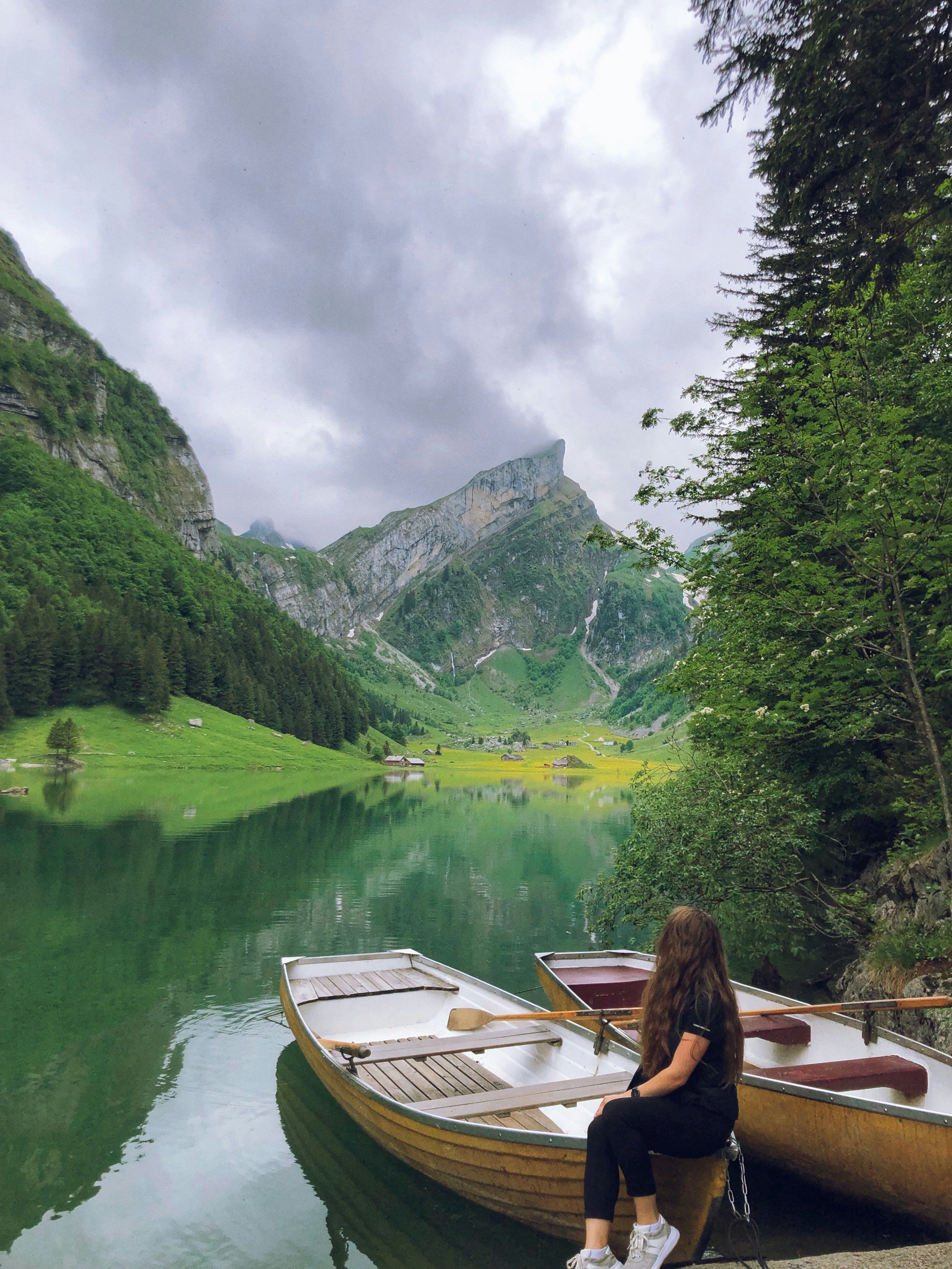 a person sitting in a boat on a river with mountains in the background