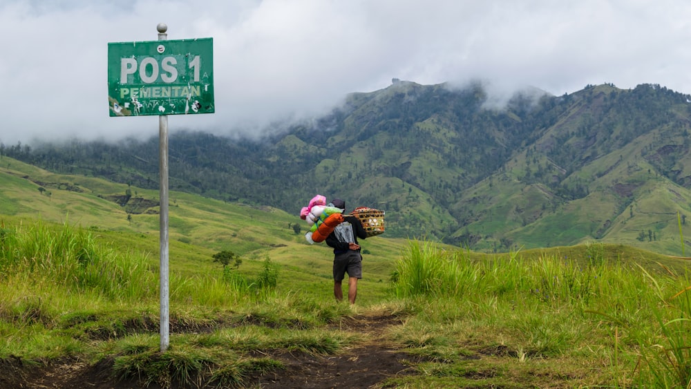 a person carrying a backpack walking on a dirt path in a grassy area