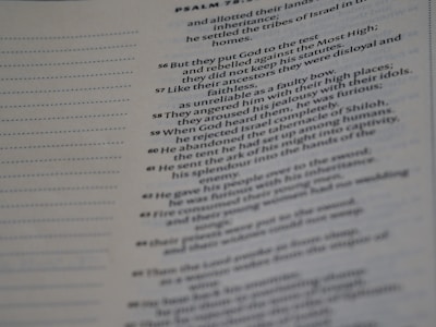 A close-up of a page from a religious text focuses mainly on a few highlighted verses. The text is printed in a serif font with traditional chapter and verse numbers. The left side of the page has a dotted margin designed for notes.