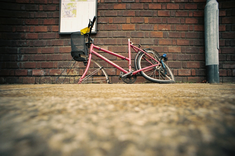 a pink bike parked on a brick wall
