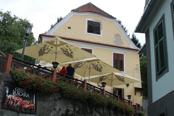 A café terrace below a yellow house — Sighișoara, Romania