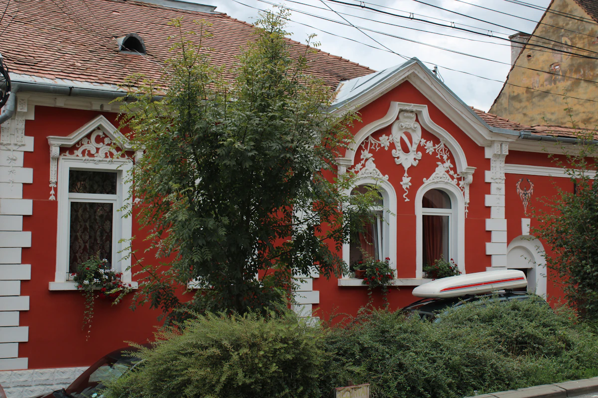 Cazare în Sighișoara: casă cu fațadă roșie decorată pe o stradă din oraș