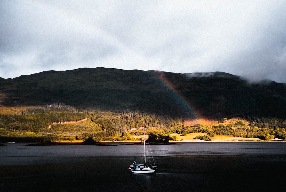 a boat on the water with a rainbow in the background
