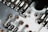 A close-up view of a circuit board showing metallic tracks, solder points, and various electronic components. The image highlights the intricate design and small details of the board with a combination of silver, copper, and greenish tones.