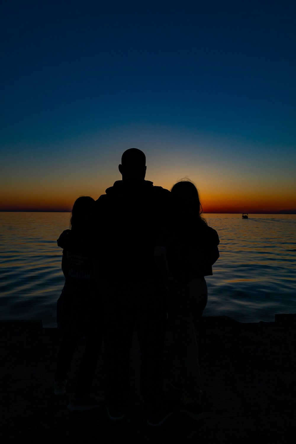 a group of people standing on a beach looking at the sunset