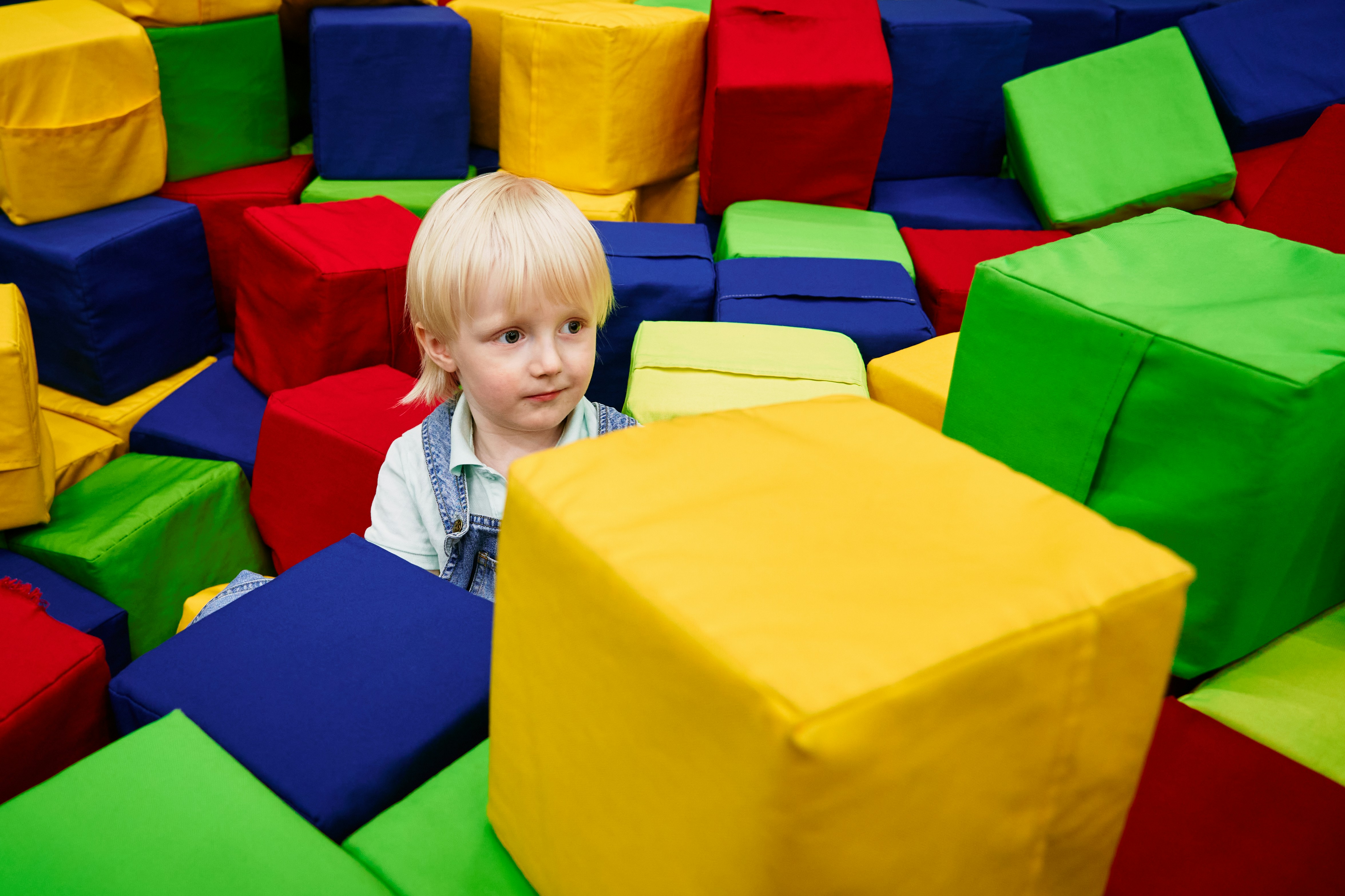 a child sitting in a large pile of colorful plastic toys