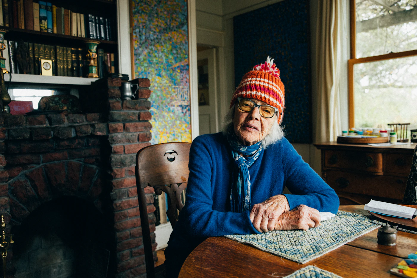 Older man in a knit hat sitting at his kitchen table