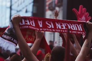 A group of fans waving bright rally towels at a lively sports event, all printed with matching team slogans.
