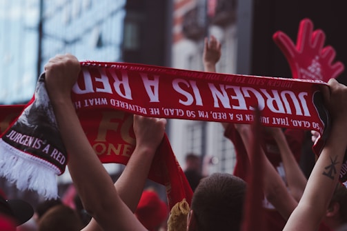 A smiling family holding keys to their new home, with red and black team scarves.