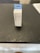 A box labeled 'FreshWater Phosphate Test Strips' with a hanging tab is placed on a dark, textured surface. The box is primarily white with blue accents and text.