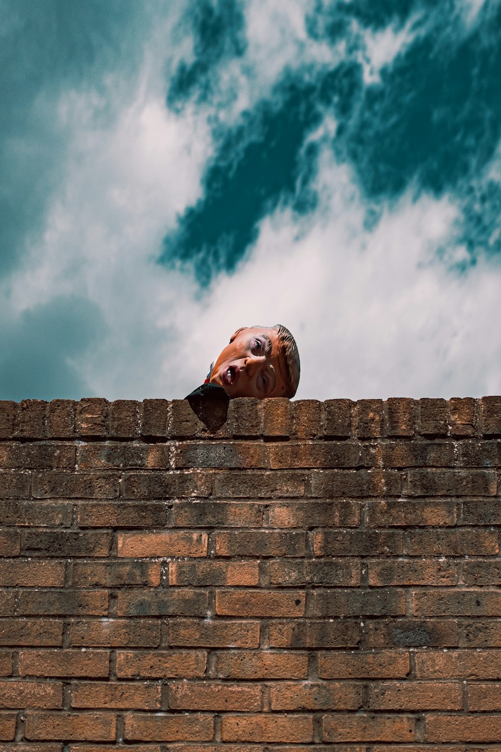 une personne souriante et debout sur un mur de briques